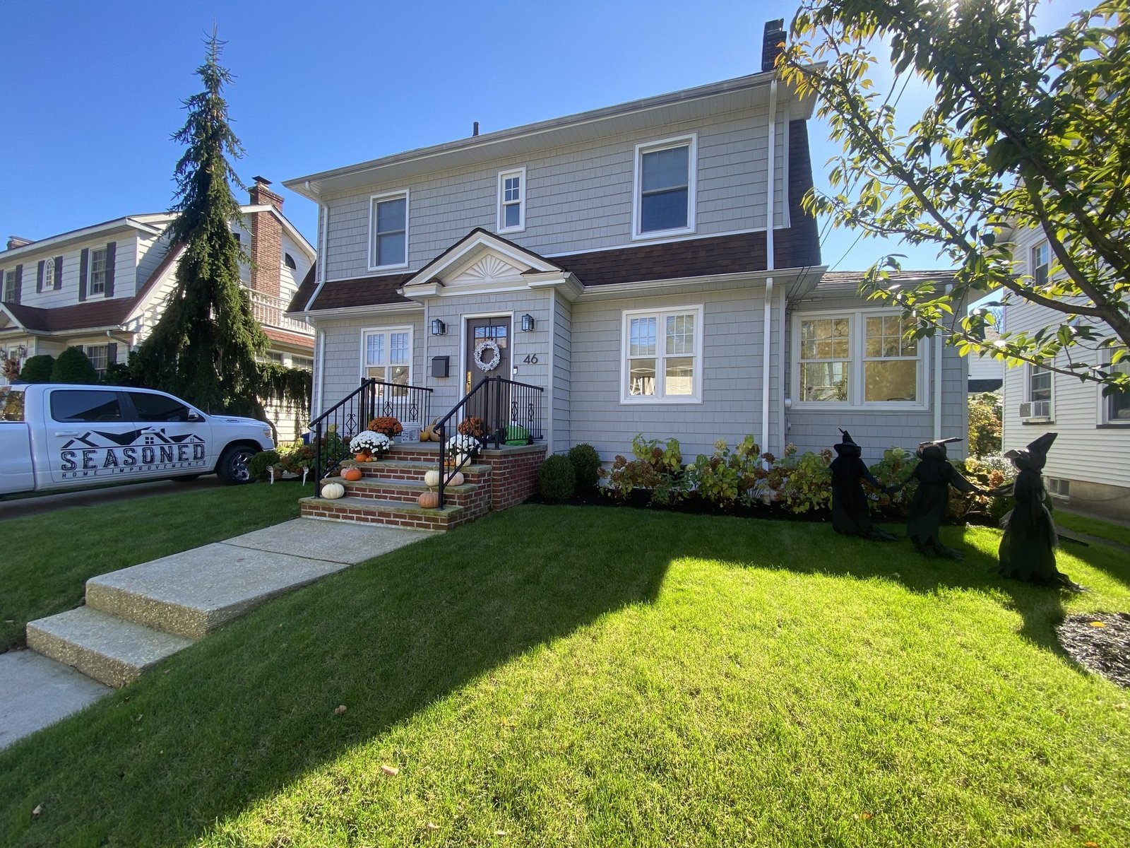 Exterior home renovation in Staten Island, NY, featuring new siding, a welcoming porch, and a well-maintained lawn by Seasoned Home Improvements.